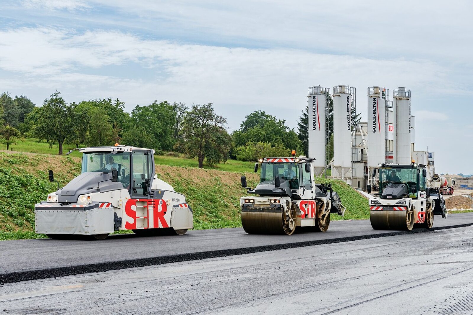 Baumaschinen teeren eine Strasse frisch