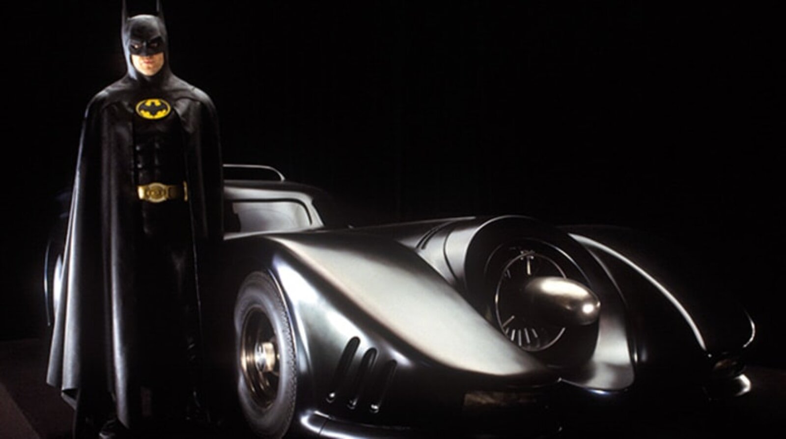 Michael Keaton als Batman neben dem Batmobil aus dem Film von 1989.