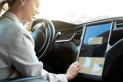 Frau bedient Touchscreen im Auto