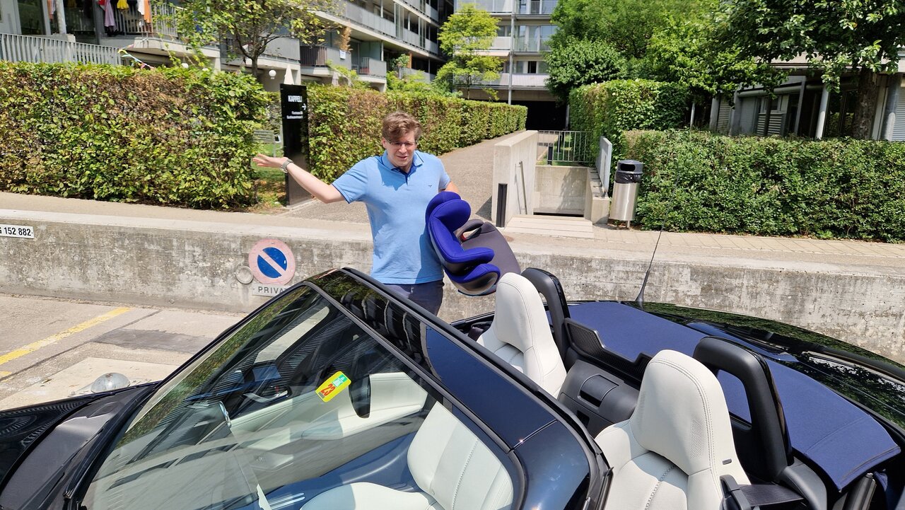 Auto-Checker Martin A. Barthold steht ratlos mit Kindersitz neben dem Mazda MX-5