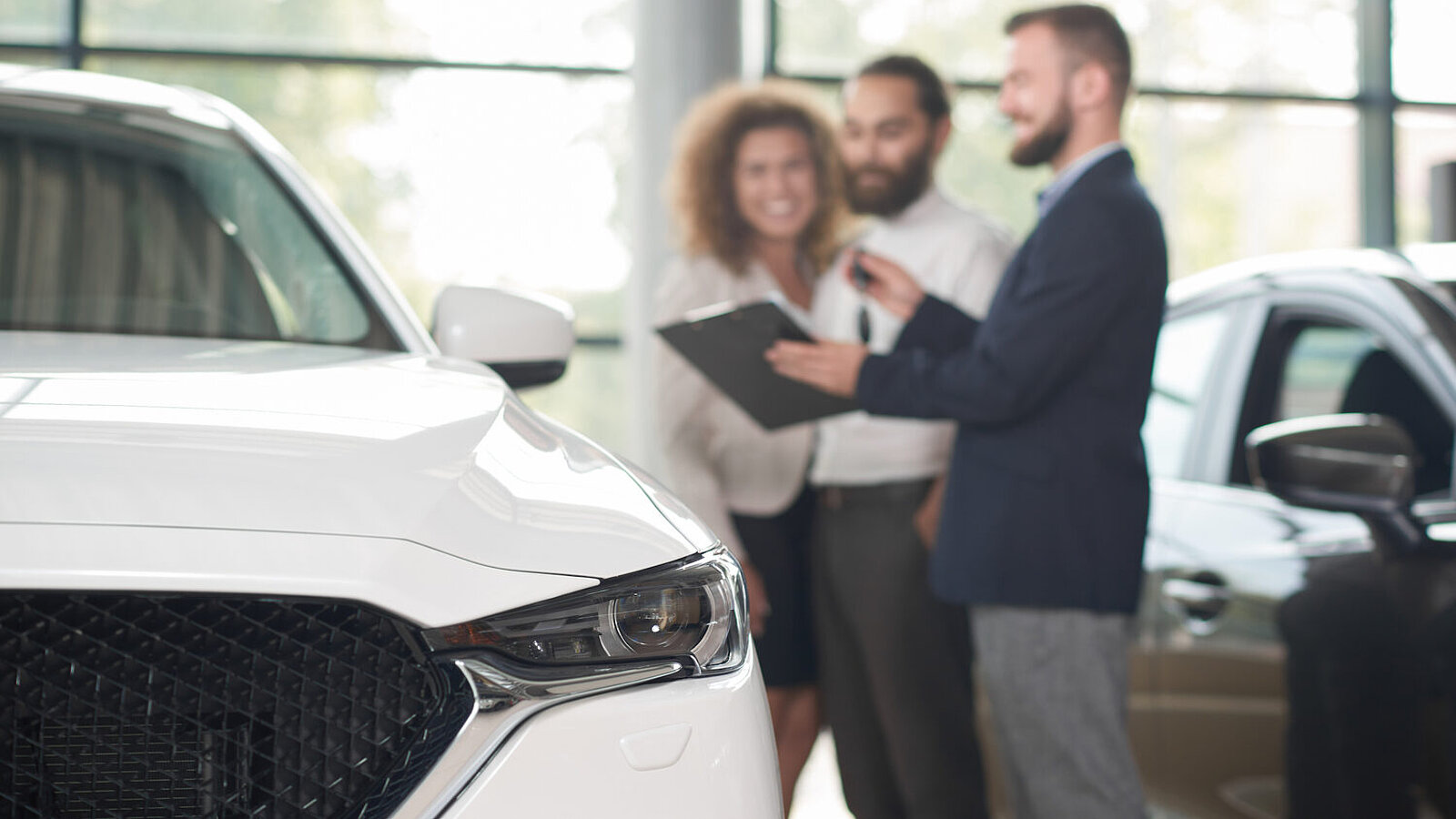Blick über die Motorhaube eines Autos auf ein Verkaufsgespräch