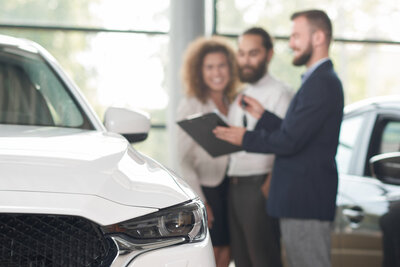 Blick über die Motorhaube eines Autos auf ein Verkaufsgespräch
