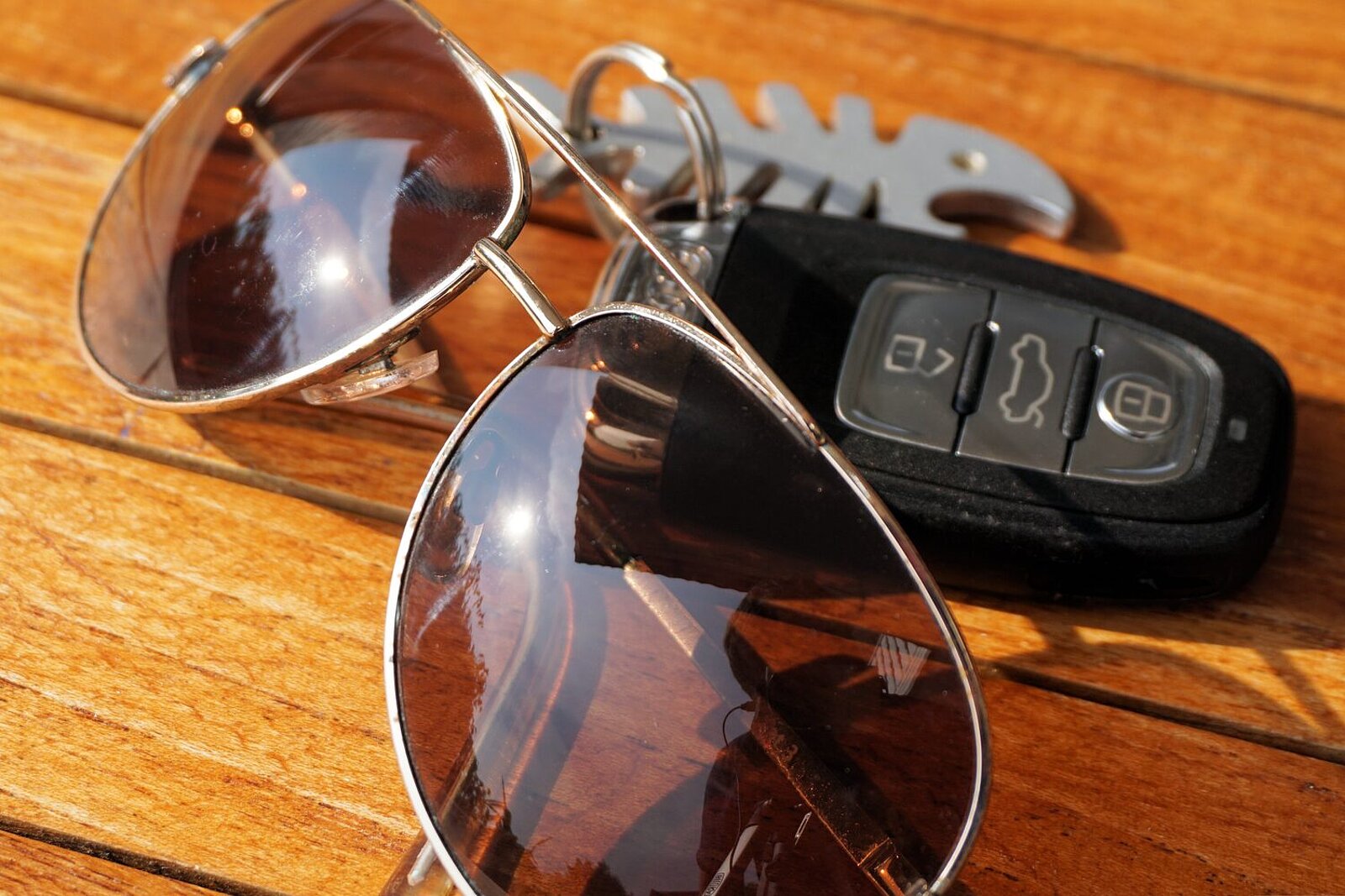 Autoschlüssel mit Sonnenbrille auf einem Holztisch