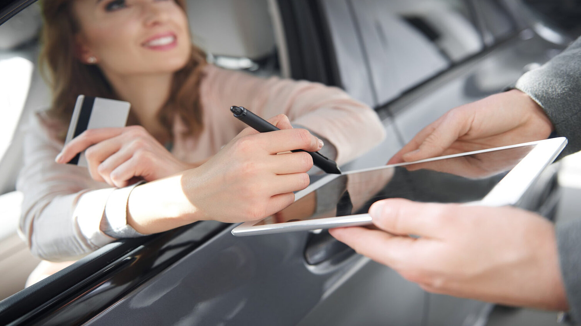 Eine Frau unterschreibt aus einem Auto heraus