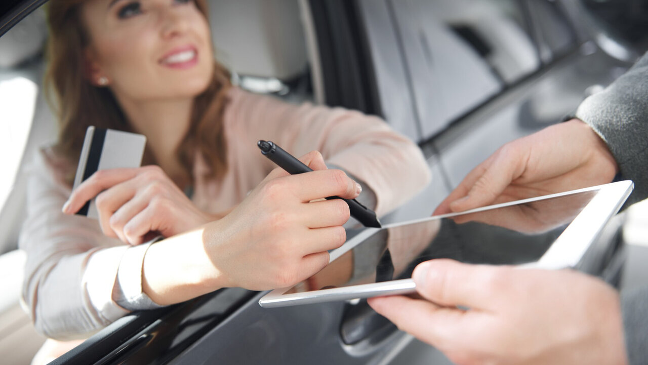 Eine Frau unterschreibt aus einem Auto heraus