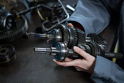 Getriebebauteile in der Hand einer Mechanikerin
