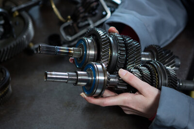 Getriebebauteile in der Hand einer Mechanikerin
