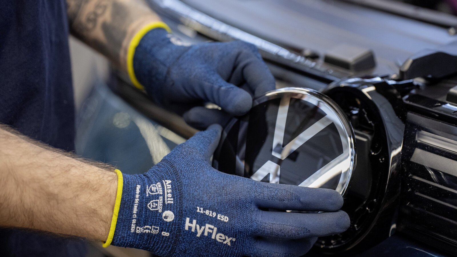 Hand setzt VW-Logo bei einem Auto ein