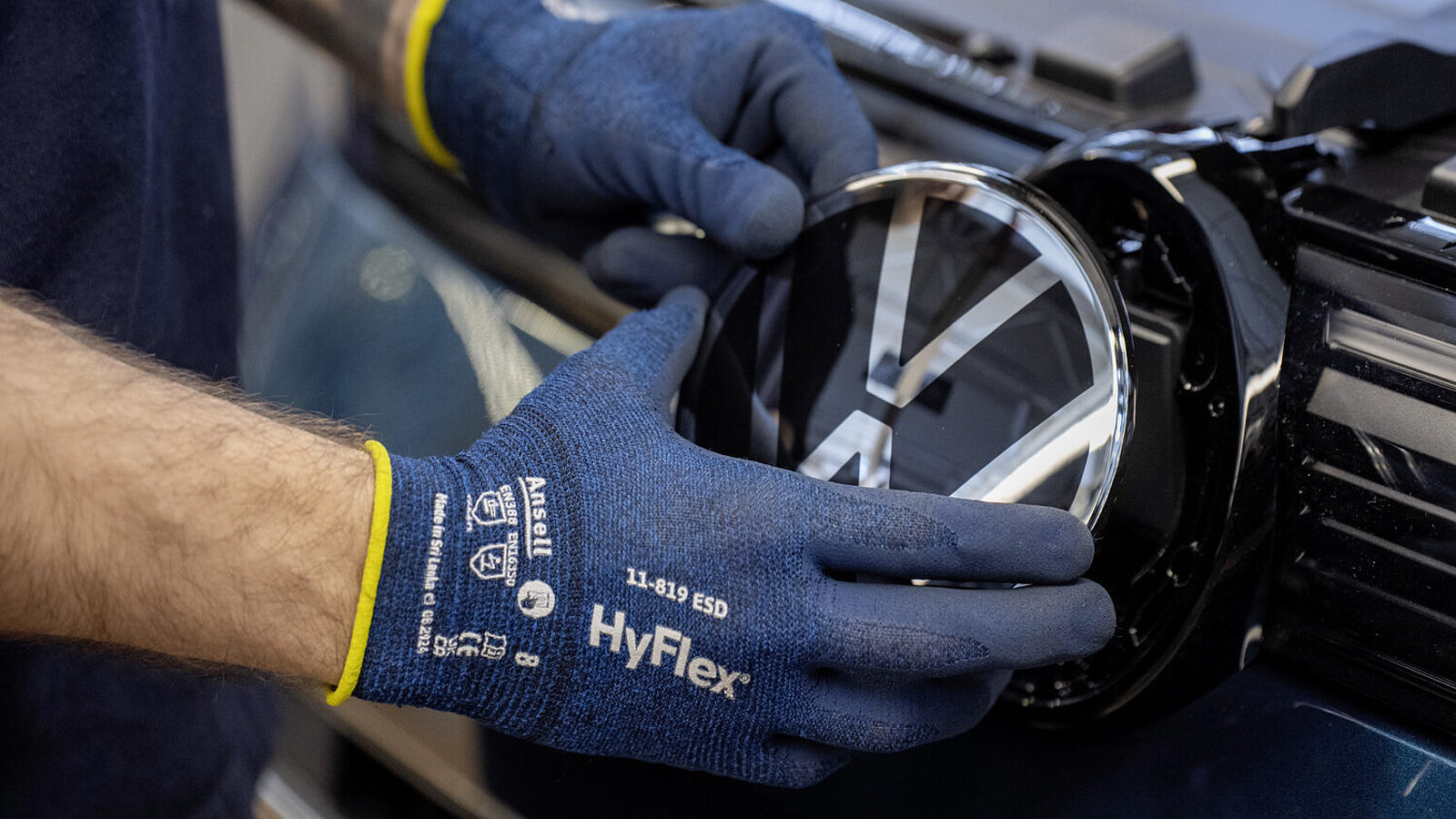 Hand setzt VW-Logo bei einem Auto ein