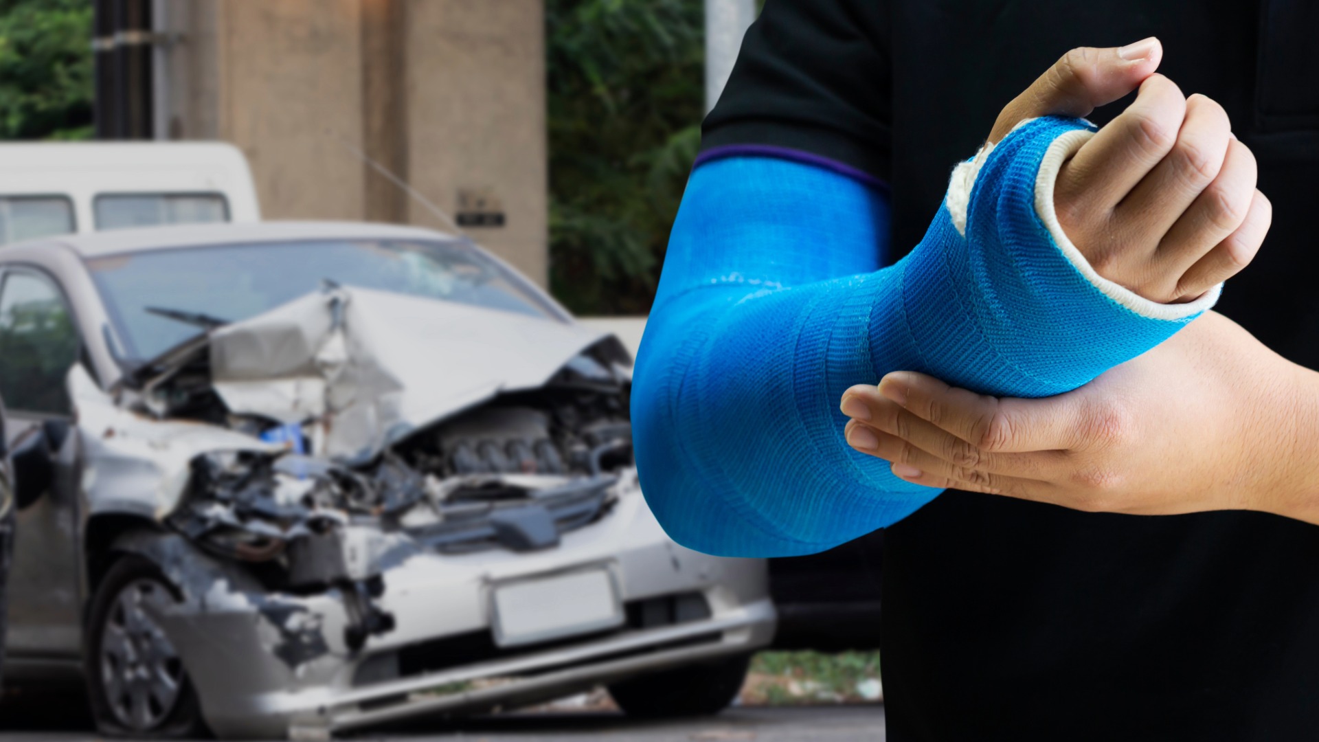 Person mit Arm im Gips vor verunfalltem Auto