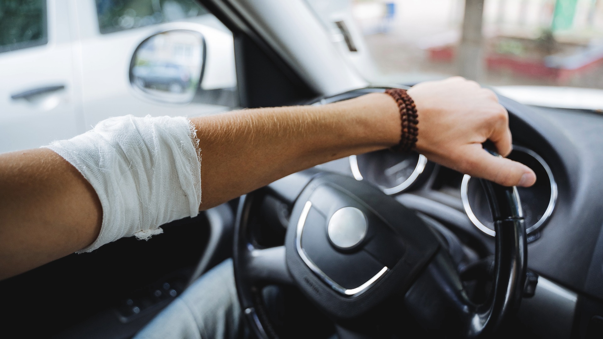 Person mit Verband am Steuer