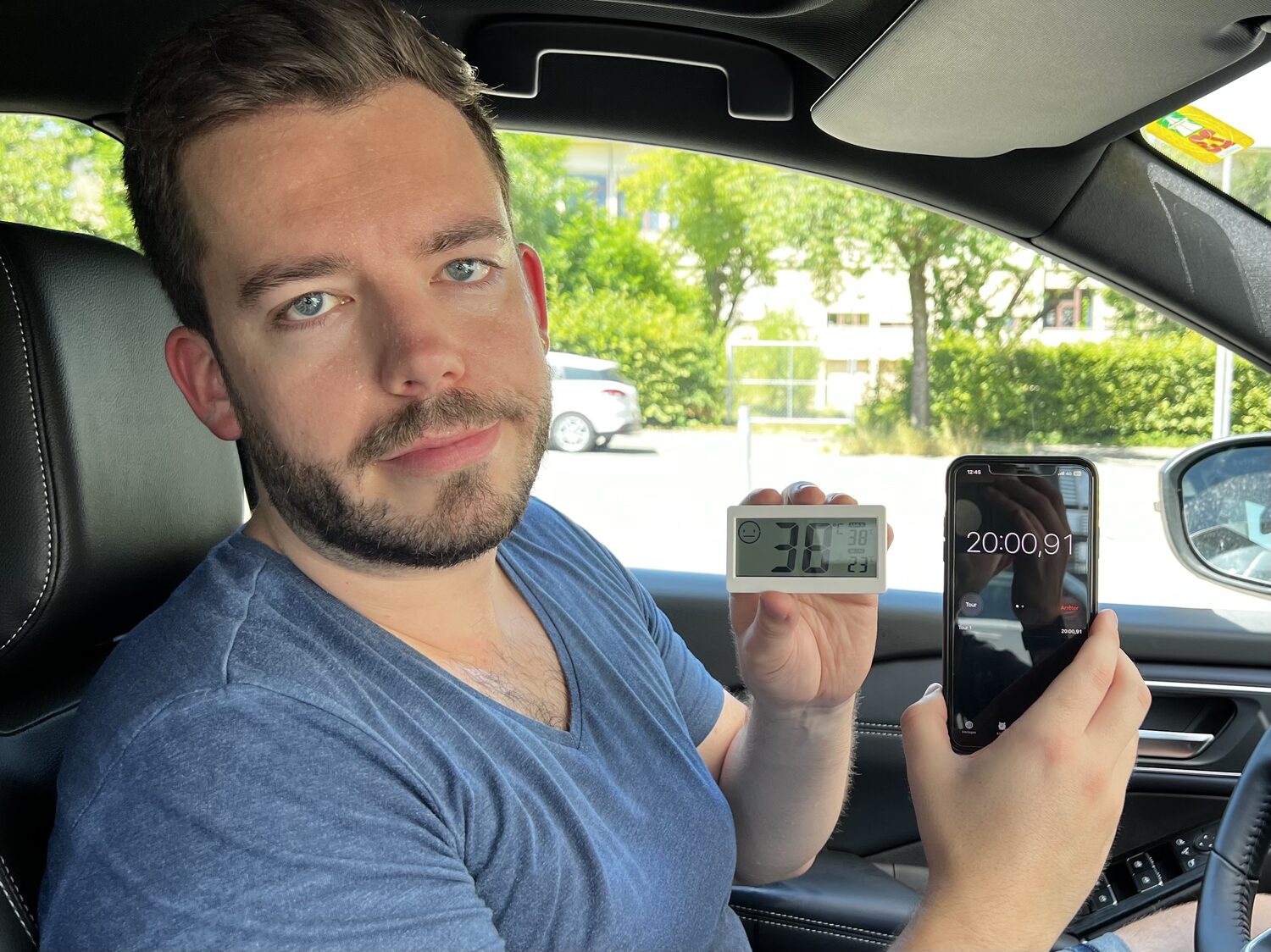 Redaktor Linus Barta mit Thermometer und Telefon in der Hand im Auto