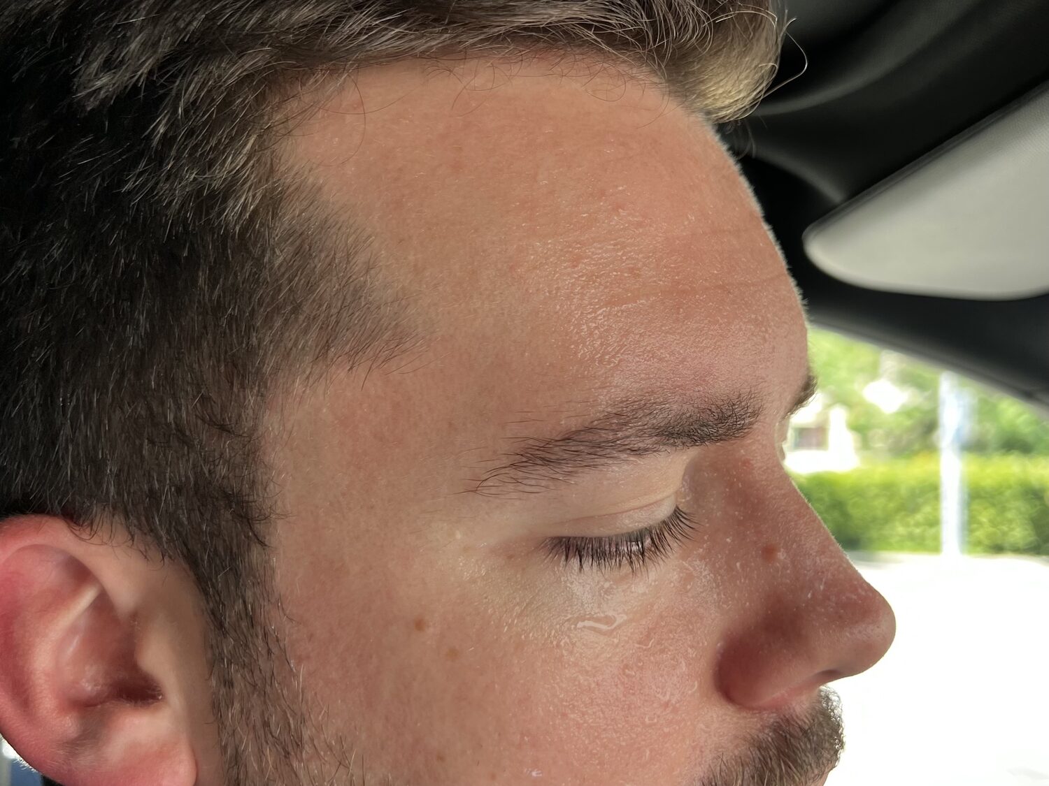 Redaktor Linus Barta mit Thermometer und Telefon in der Hand im Auto